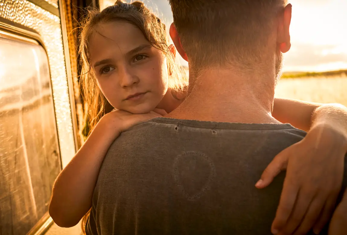Mädchen guckt über die Schulter ihres Vaters – ob sie an Langnese Honig denkt?